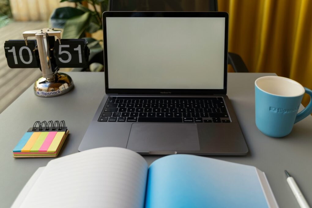 desk with computer, mug, notes, notebook, and pen